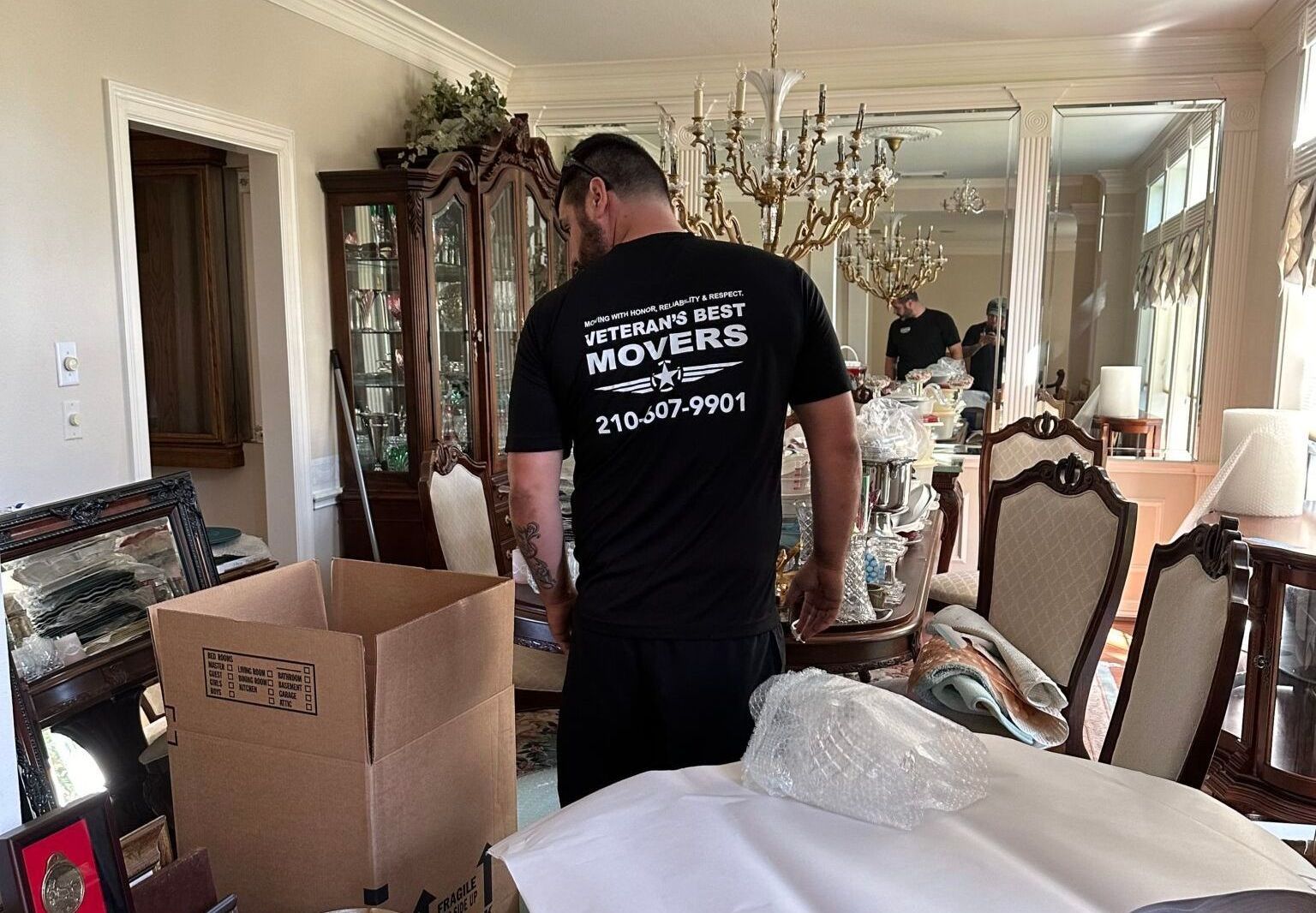 A man wearing a movers shirt is standing in a living room.